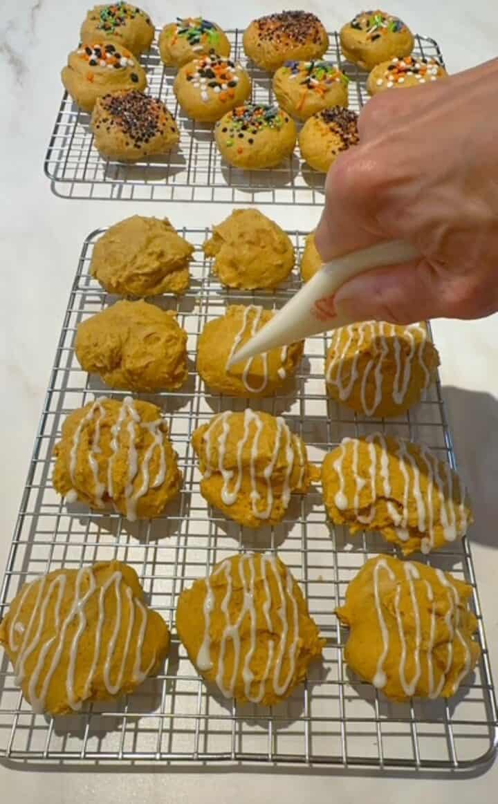 Deep amber pumpkin ricotta cookies are iced with a white glaze as they sit on a wire rack.