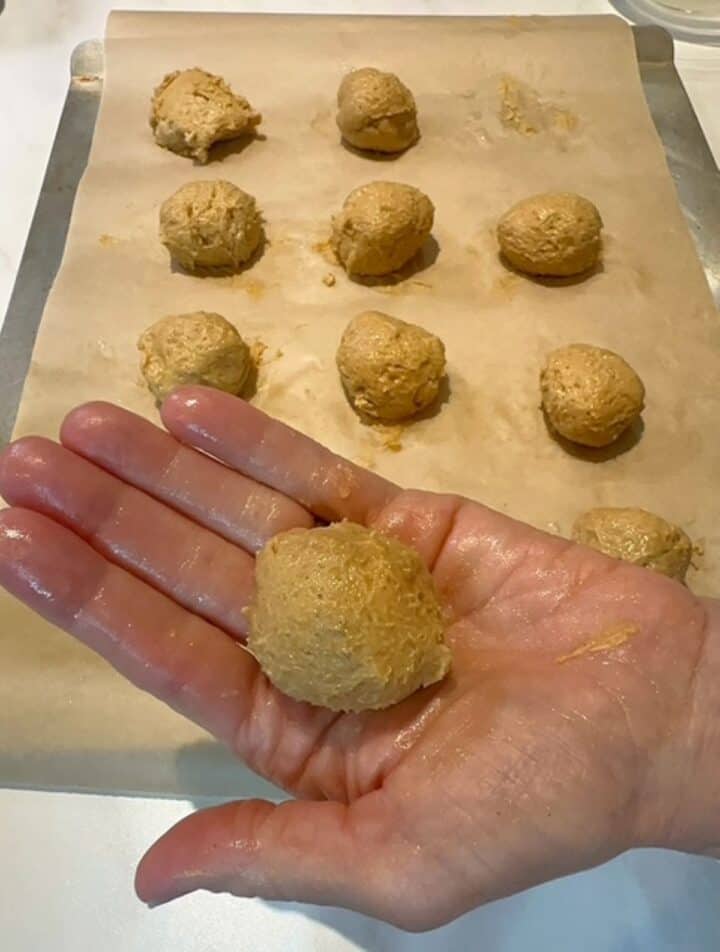 A moist palm holds a golden ball of pumpkin ricotta cookie dough.