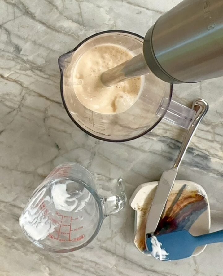 A stick blender purees a creamy banana peanut butter smoothie.