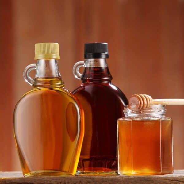 Light and dark brown bottles of maple syrup plus a small amber bottle of honey.