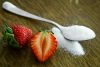Spoon full of white sugar with red strawberry