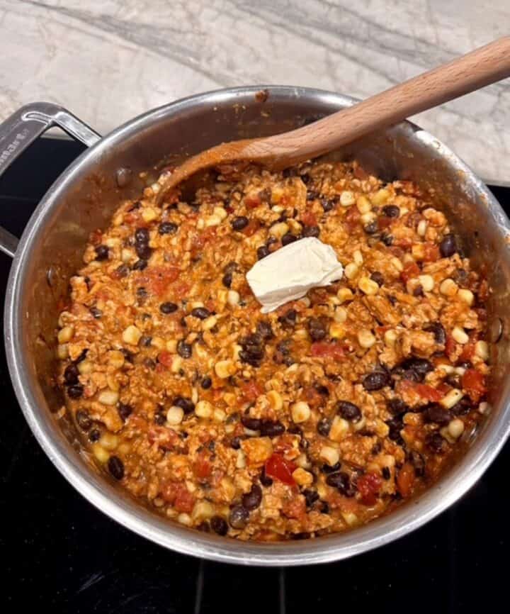 A white knob of cream cheese sits on top of a meat-bean-corn mixture for taco filling.