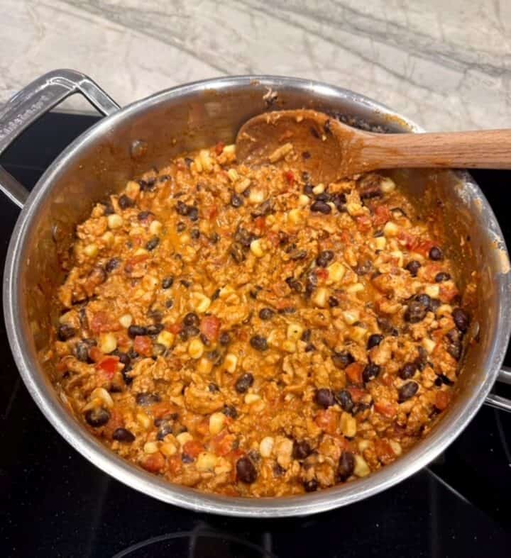 Creamy orangish taco meat-bean-corn mixture in a silver metal skillet.