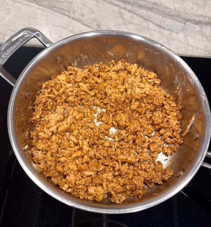 Silver aluminum skillet filled with golden, cooked meat crumbles.