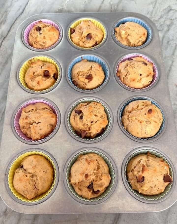 A dozen baked banana peanut-butter-powder muffins still in muffin tin.