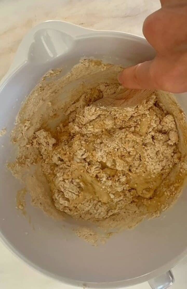 Mixing a light colored batter for peanut butter powder muffins in a white batter bowl.