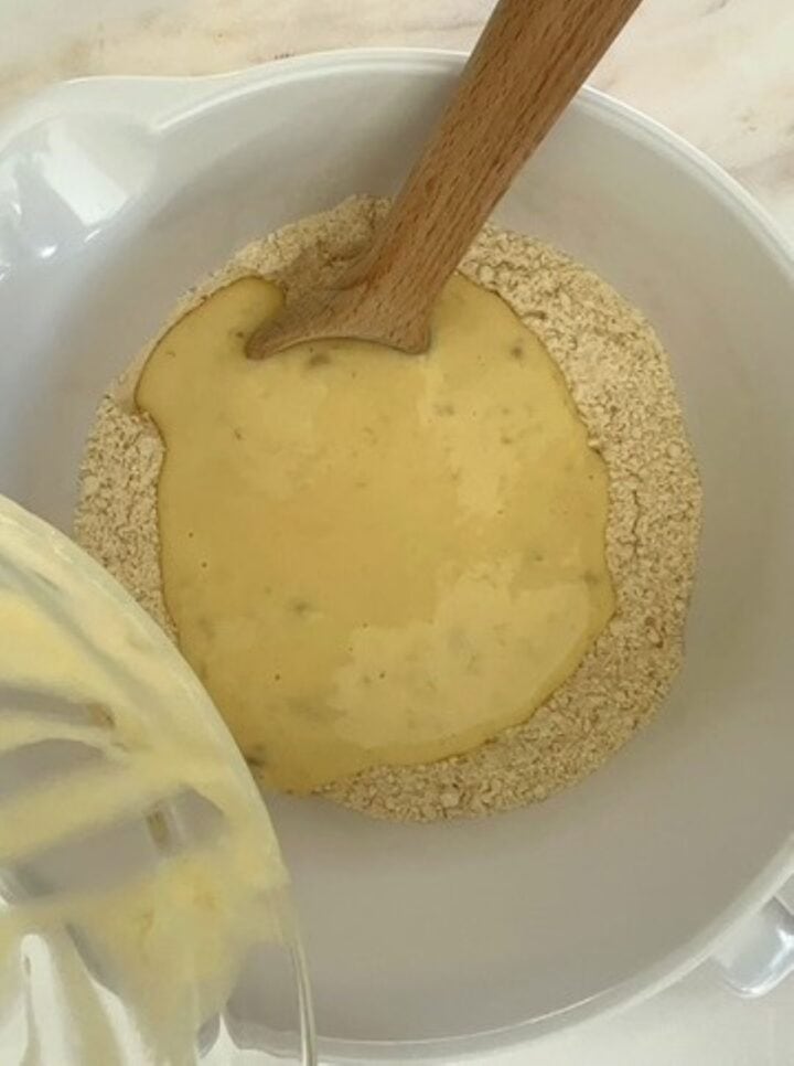 Creamy wet ingredients in a well created by floury ingredients for peanut butter powder muiffins.