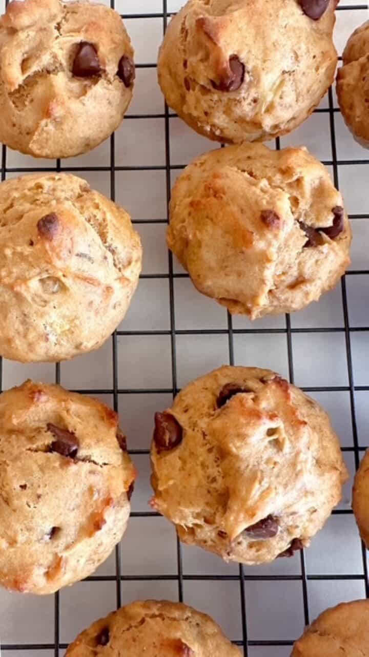 Banana peanut butter muffins studded with chocolate chips on a dark cooling rack.
