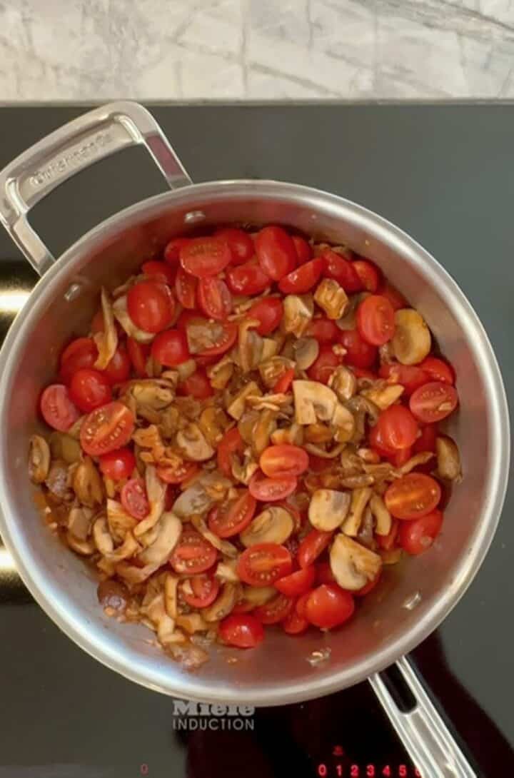 A load of halved, red cherry tomatoes are added to mushrooms to make a thick sauce for creamy baked polenta.