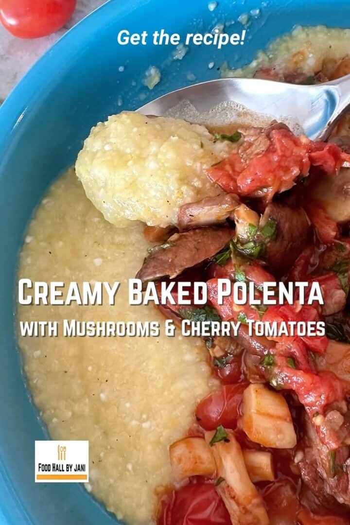 Large closeup of a spoon holding a bite of golden, creamy polenta with bits of spft, red tomato and cooked brown cremini mushroom flecked with green herbs.