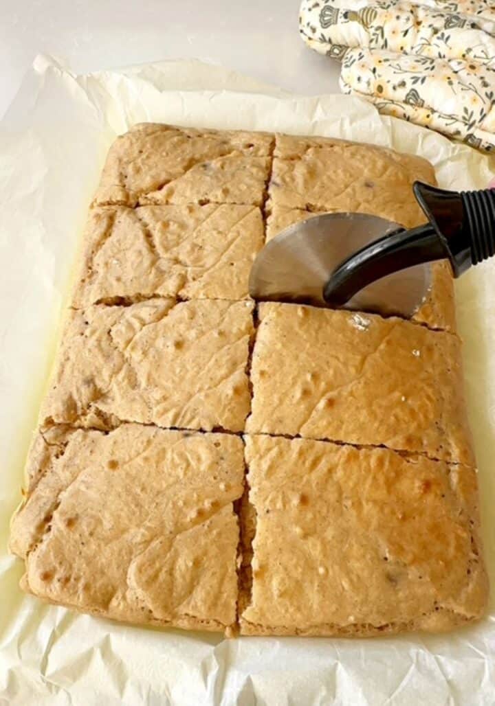 Using a pizza cutter to cut a sheet pan pancake into smaller sqaures.
