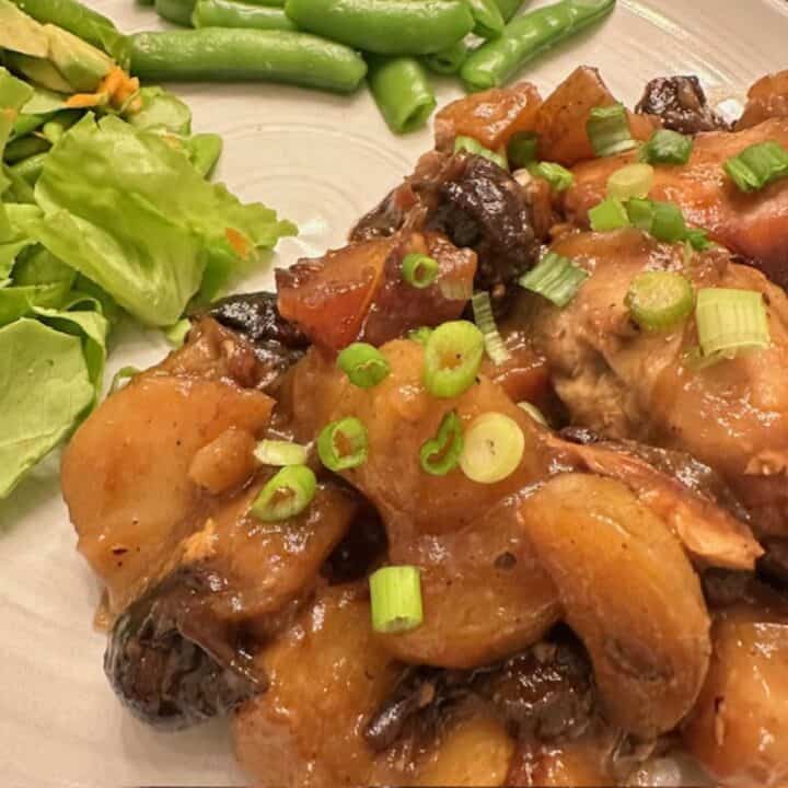 Saucy slow-cooked chicken, potatoes, and dark prunes are wrapped in a caramel-colored sauce and topped with green onions.
