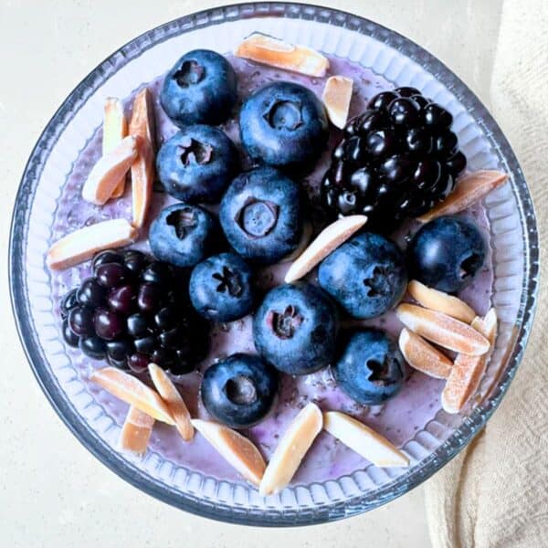 Round bowl of blueberry chia pudding topped with dark berries.
