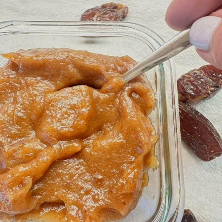 Thick, caramel-colored date paste in a clear square glass storage container.