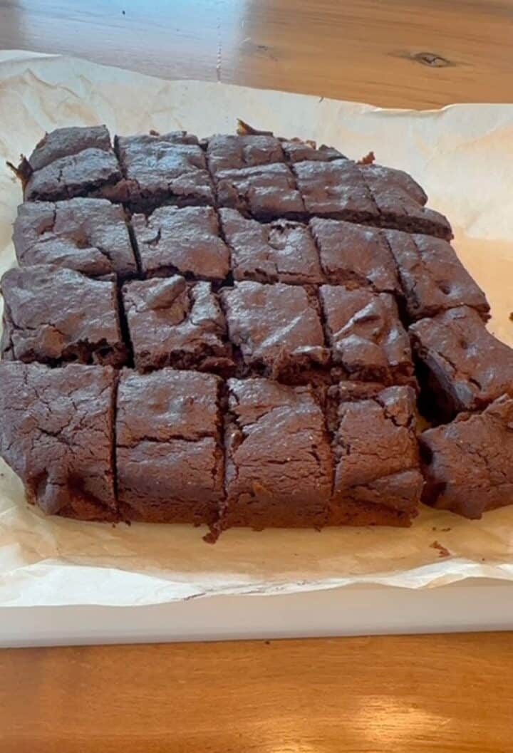 Whole batch of brown chocolate date paste brownies cut into small squares.