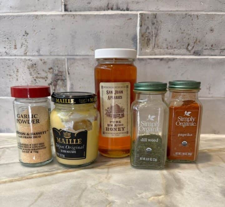Assorted spices and a honey jar for salmon glaze on kitchen counter.