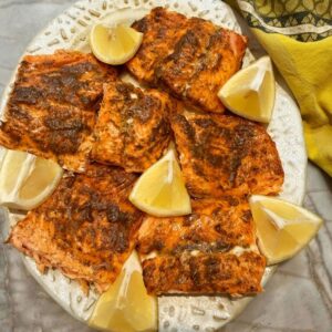 Baked salmon with honey, Dijon, dill glaze and lemon wedges on a plate.