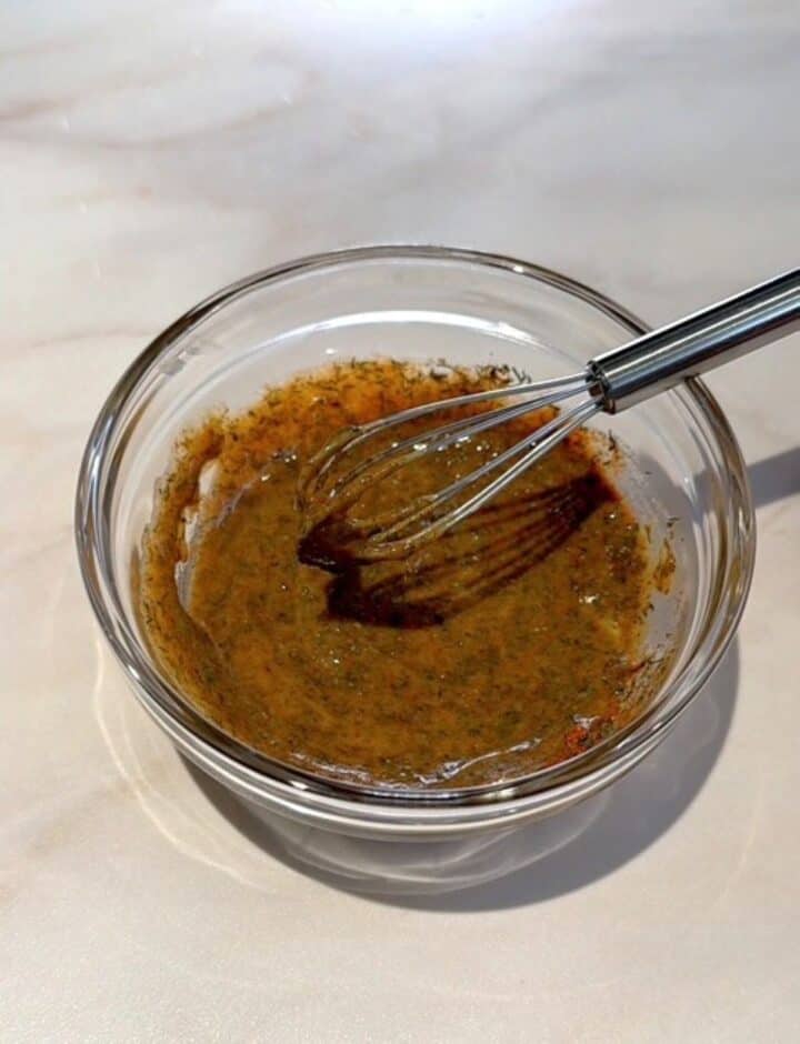 Honey-mustard-dill glaze ingredients are whisked in a small clear bowl.