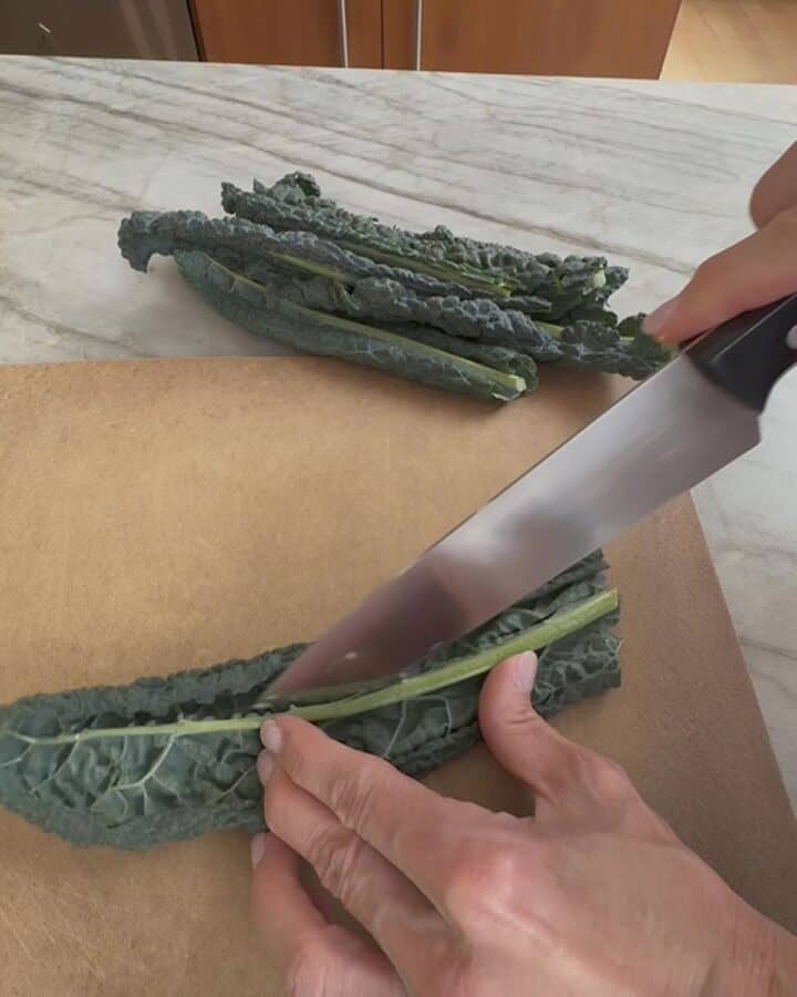 Person prepping kale on a cutting board at Food Hall by Jani.