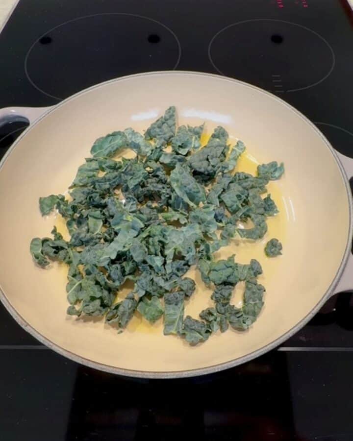 Cooking kale in a skillet with olive oil for a healthy side dish.