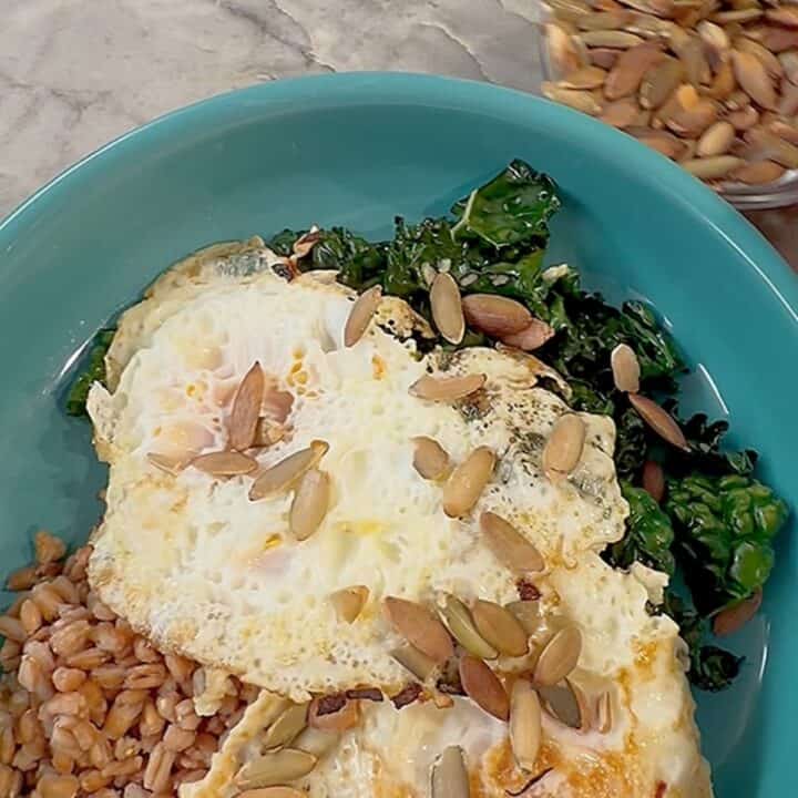 Healthy kale and zucchini breakfast bowl with pumpkin seeds and eggs.