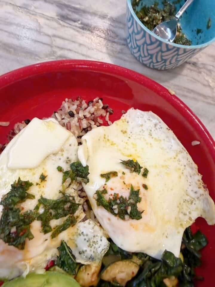 Healthy breakfast bowl with eggs, kale, and zucchini and herbal mint gremolata.
